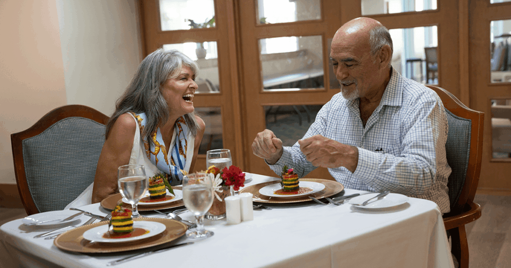 A couple enjoys a meal together at an elegant restaurant table with plates and glasses of water.