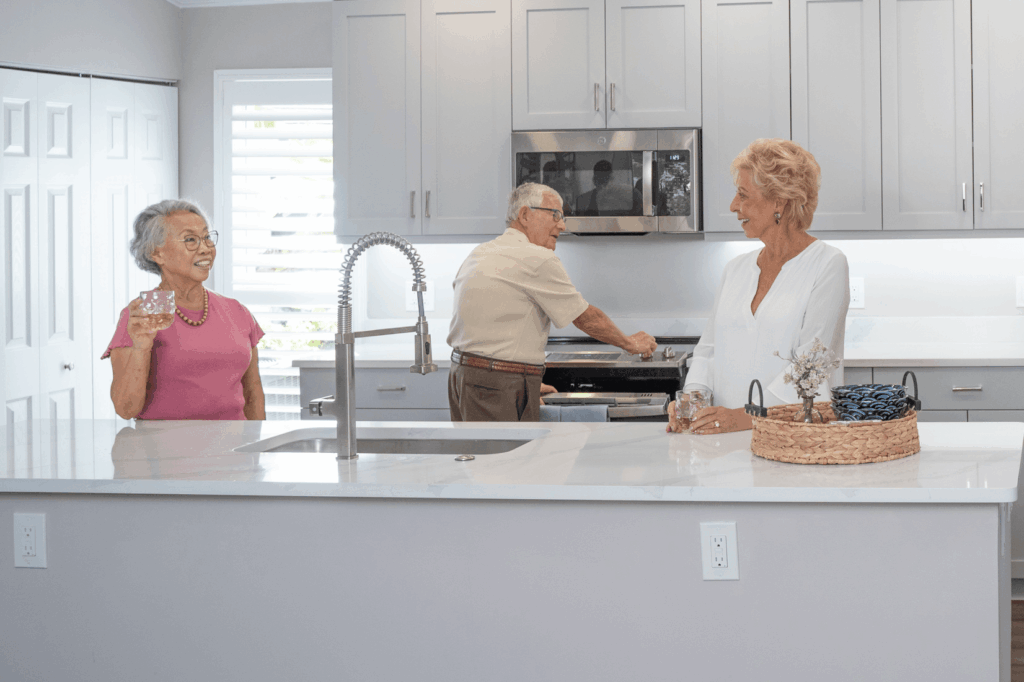 Three people interact near kitchen island with modern appliances and decor.