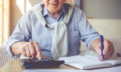 elderly man calculating the cost of senior living on a calculator