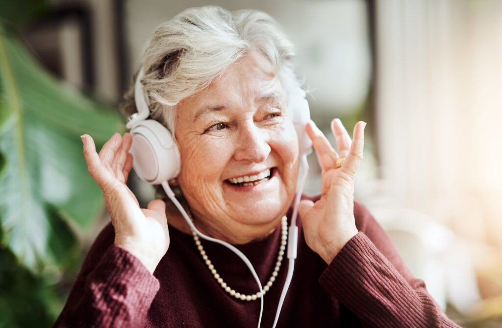Smiling senior woman listening to music through headphones.
