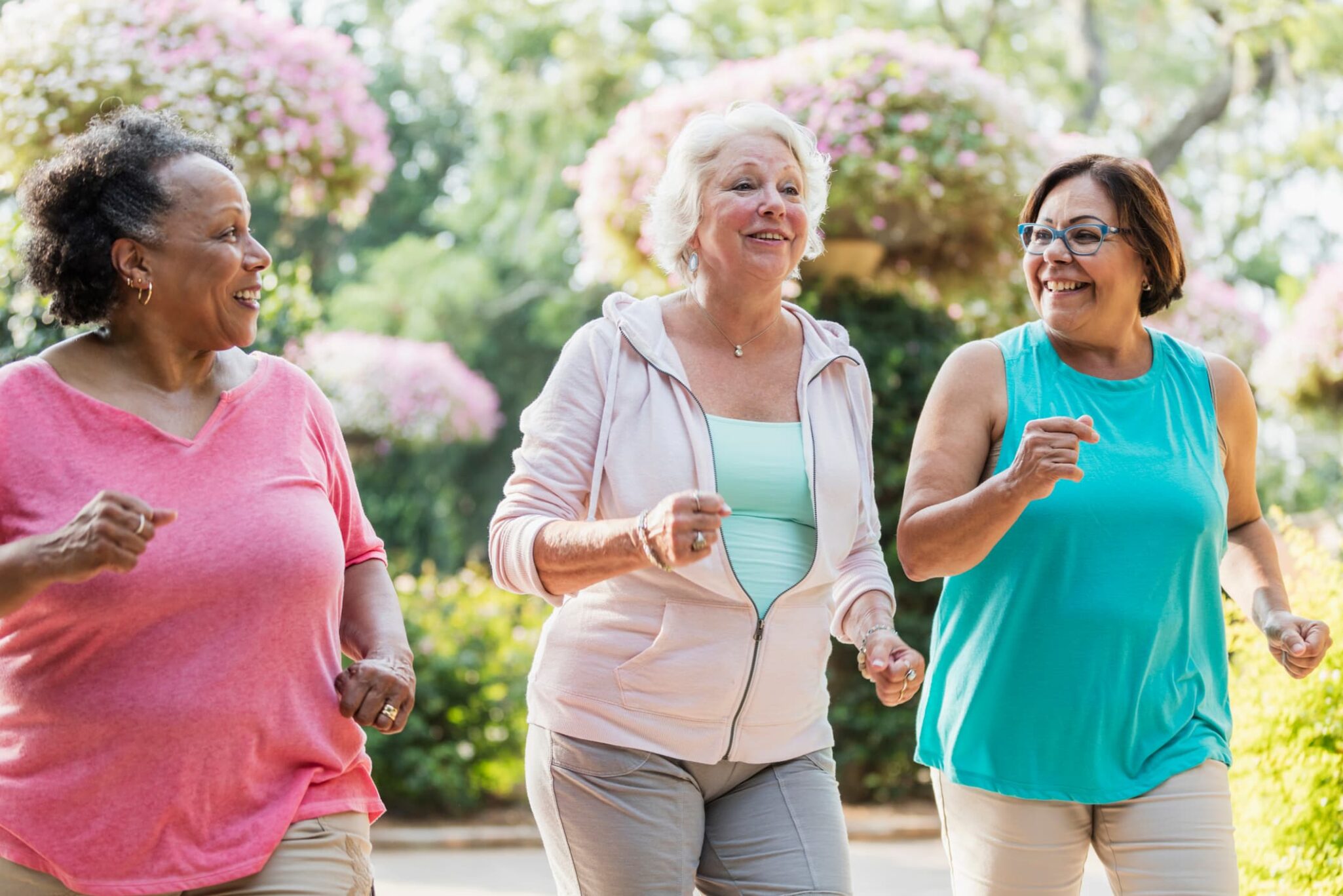 Three older women walking together outside.