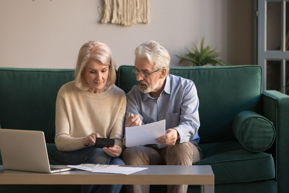 senior couple looking at paperwork while sitting on the couch