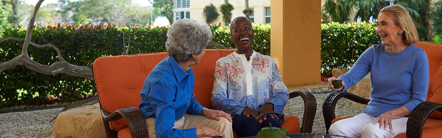 Three ladies chatting while sitting outside of their Delray Beach retirement community